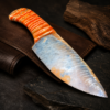 Handcrafted flintknapped stone knife made from Agatized Florida Coral by Joel Robinson featuring a blue-gray blade and dyed orange Woolly Mammoth tooth handle.