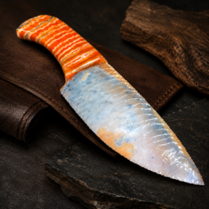Handcrafted flintknapped stone knife made from Agatized Florida Coral by Joel Robinson featuring a blue-gray blade and dyed orange Woolly Mammoth tooth handle.