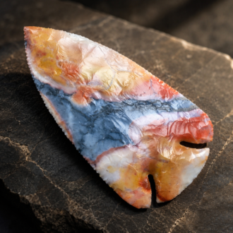 Handcrafted Deep Notched Lost Lake point flintknapped from colorful Flint Ridge Flint, featuring vibrant natural bands of red, blue, cream, and gold by Joel Robinson.